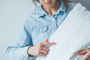 Faceless female pointing finger bed bugs on a white pillow. Health problems and sleep disorders