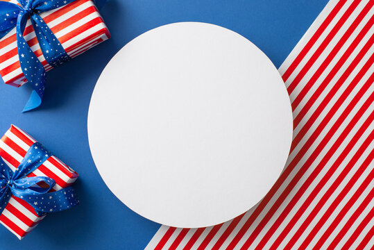 Captivating scene of USA celebration. Top-down view captures beauty of symbolic elements— gift boxes in thematic wrapping on American flag backdrop with blank circle for text or promotional purposes