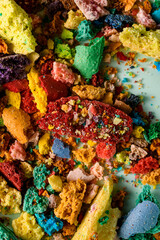 Crushed and broken different colored parts of french dessert macaron laying chaotically on green background