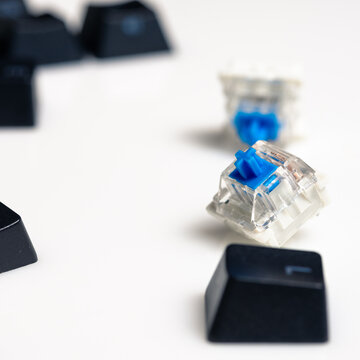Keycaps and Keyswitch for Mechanical Keyboards Scattered on White Background