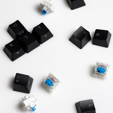 Keycaps and Keyswitch for Mechanical Keyboards Scattered on White Background