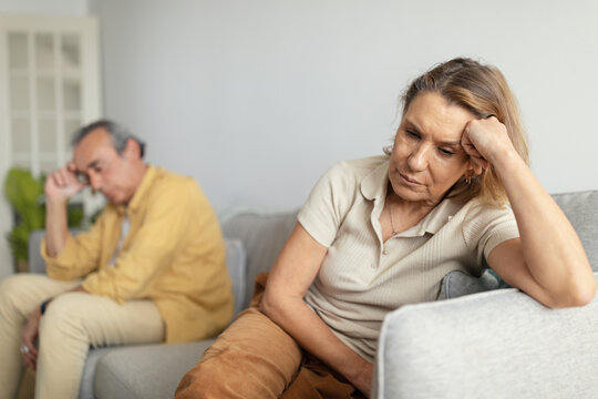 Despaired european senior woman ignoring husband after quarrel, sitting together on sofa, selective focus