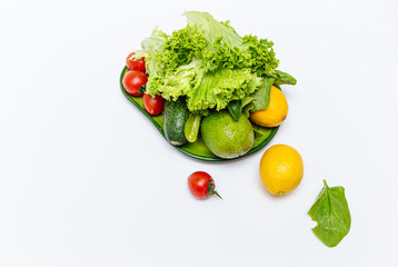 Bundle of  ripe fresh vegetables. Green lettuce, red cocktail tomatoes, avocadoes, lemons. White kitchen background.