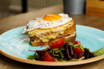 Classic french toast with cheese and ham, fried eggs, vegetables and honey-balsam dressing