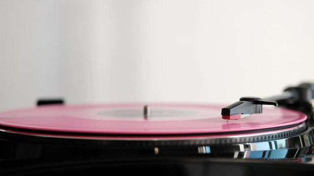 close up of a rose vinyl record spinning on turnable