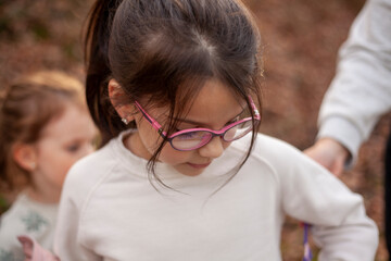 Little girl in glasses and a white T-shirt in the park
