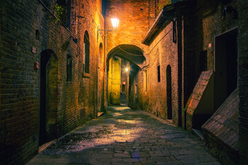 Narrow street in old town Siena at night, Italy