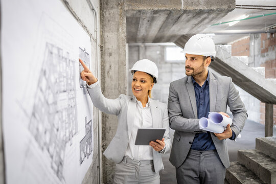 Construction inspectors working together at the site, controlling and inspecting building process. Looking at project plan and blueprint.
