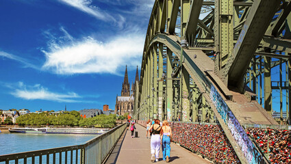 Cologne (Köln), Germany - June 6. 2023: Cycle- and footpath over Hohenzollern rhine bridge to  dome cathedral on sunny summer day