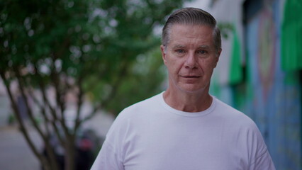 Portrait of an older man walking toward camera in city street. Close-up face of a middle-age person