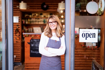 ttractive small business owner businesswoman standing with arms crossed at cafe door and waiting for guests