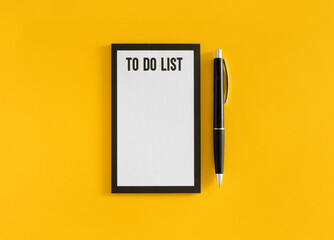White sheet with to do list phrase and black pen on yellow background. Stock photo.