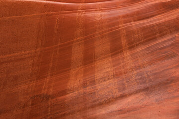 Horizontal striations in the red orange sandstone of Peekaboo Canyon in Southern Utah are crossed...