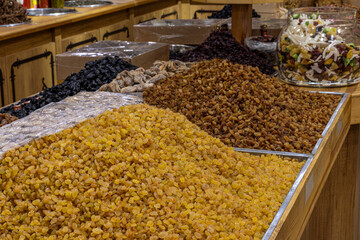 Raisins are heaped on the counter of a store or in the market. Dried fruits. Golden dried grapes without seeds on the market counter.