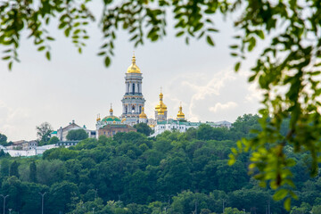 Fototapeta na wymiar In summer, through the branches of trees, you can see the Kyiv Lavra