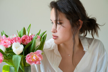 portrait of caucasian brunette girl with big bouquet flowers of tulips