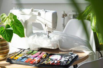 Sewing layout with multicolored spools of thread close-up, needles, electric sewing machine....