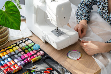 Woman hand close up sews tulle on electric sewing machine. Filling the thread into the sewing...