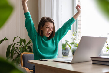 Online Win. Happy  Woman Celebrating victory Success With Laptop. Female Raising Hands Up And Screaming Yes. triumph gesture.