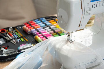 Sewing layout with multicolored spools of thread close-up, needles, electric sewing machine....