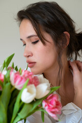 portrait of caucasian brunette girl with big bouquet flowers of tulips