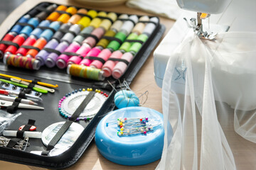 Sewing layout with multicolored spools of thread close-up, needles, electric sewing machine. Filling the thread into the sewing needle, adjusting the tension. hobby, home business