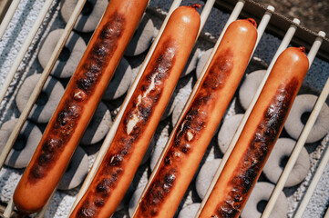 Top view on cooking sausages on grill. Top view. Picnic outdoors