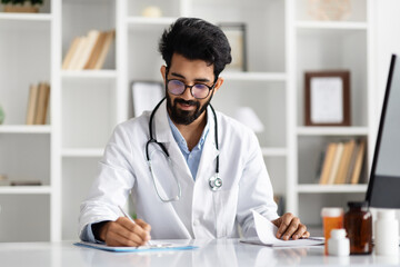 Middle eastern family doctor working at his office at clinic - obrazy, fototapety, plakaty