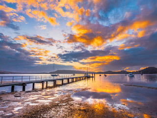 Obraz premium Aerial sunrise over the water with low cloud cover, boats and reflections