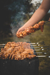 Man hand grilling barbecue with smoked pork at backyard on day. Family dinner outdoor style bbq activity