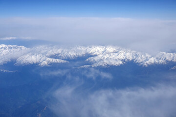 View of the high snow-capped peaks of the Main Caucasian Range from the window of a flying aircraft