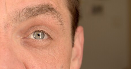 Naklejka premium The left eye of the man play with the eyebrow. Demonstration of a playful mood with a part of the body. Visual expression of emotion.