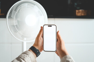 Phone in hands against the background of an electric fan, smart home concept