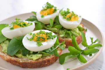 Breakfast avocado toast with hard-boiled eggs garnished with herbs