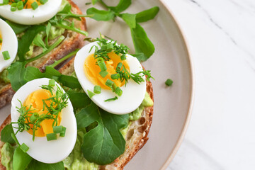 Breakfast avocado toast with hard-boiled eggs garnished with herbs