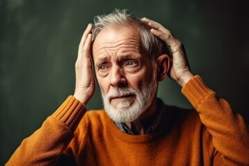 Bearded senior man putting hands on head feeling discomfort on dark grey background