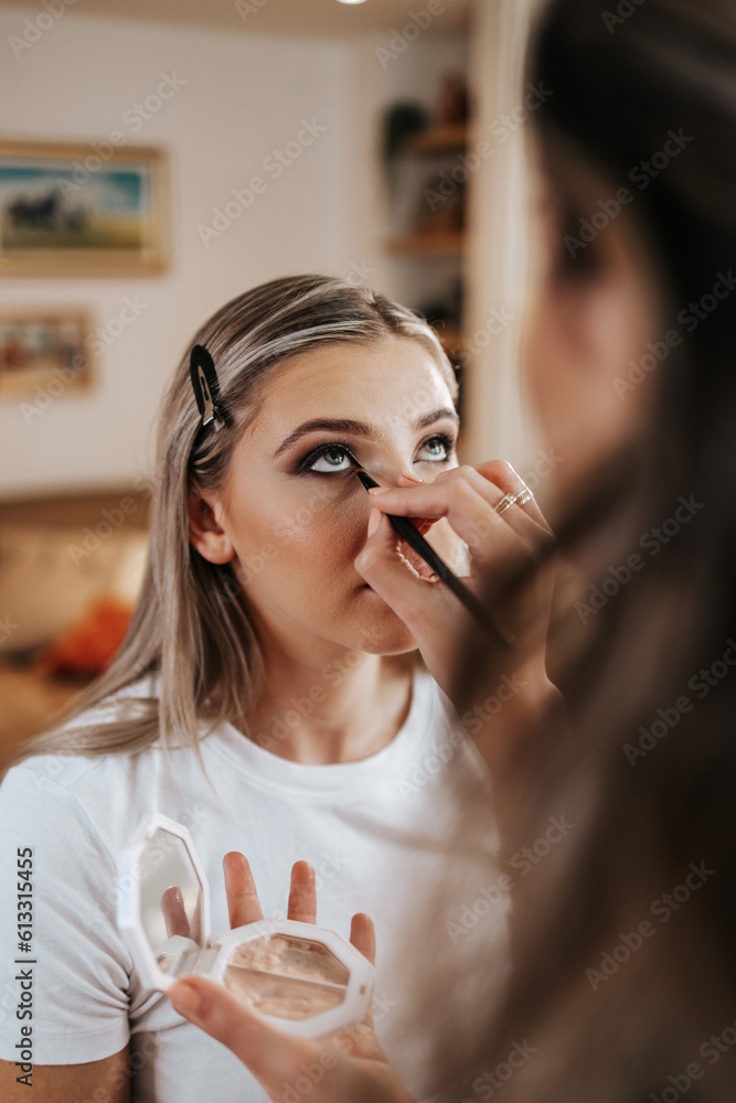 Wall mural makeup process. professional artist applying make up on model face. close up portrait of beautiful b