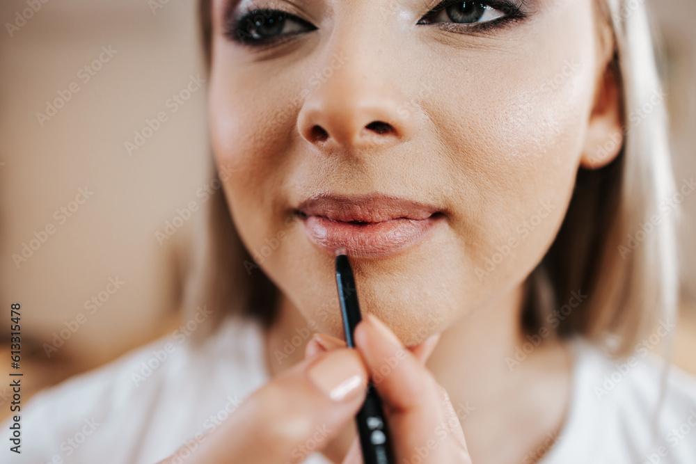 Poster Makeup process. Professional artist applying make up on model face. Close up portrait of beautiful blonde woman in beauty salon.