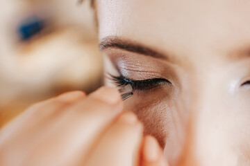 Makeup process. Professional artist applying make up on model face. Close up portrait of beautiful blonde woman in beauty salon.