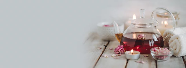Fototapete Spa Concept of natural organic flower, herbal ingredients for spa treatment for relaxation and detox. Hot tea with rose extract, petals for beauty procedures, towel, candles. Detention, meditation banner