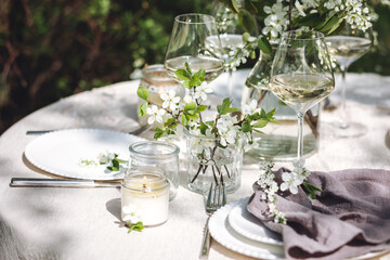 Rustic elegant eco friendly zero waste trendy wedding reception table decor with fresh spring apple cherry flowers in bloom. Beautiful marriage decoration, holiday event outdoors in the family garden