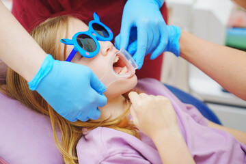 The pediatric dentist installs cheek and lip retractor for takes photos