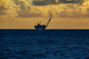 Fototapeta na wymiar Offshore oil and rig platform in the sunset or sunrise time. Construction of production process in the sea. Power energy of the world.