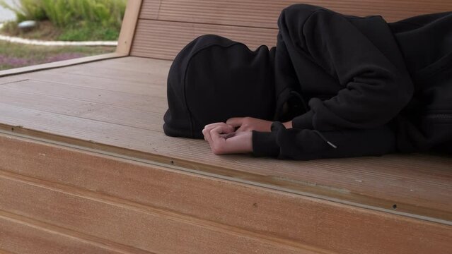 A teenager from a dysfunctional family. A teenager sleeps on a bench against the backdrop of the sea.