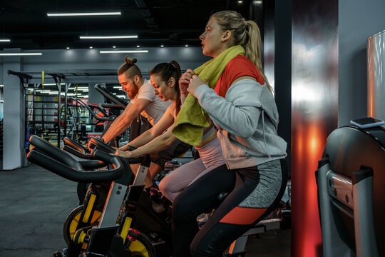 Group of people works out during a spinning session on a cycling machine at the gym with his friends.	