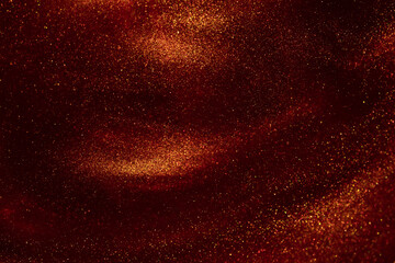 Beautiful flying shiny golden particles on a red background. Amazing golden particles in red fluid....