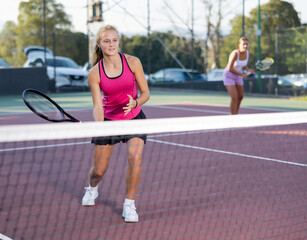 Obraz premium Young woman in skirt playing tennis on court. Racket sport training outdoors.
