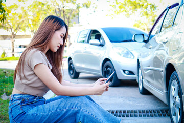 Car insurance concept. woman driving accident She uses her smartphone to call the insurance company...