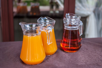 cool juice from orange pineapple mango peach apple in jugs on the table