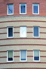 Fototapeta na wymiar a row of white rectangular windows on a brown brick wall of a large house on the street